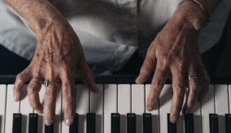 old hands of a senior woman playing the piano.